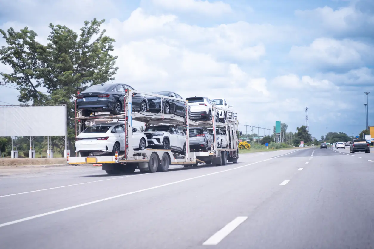 New Project (14) A truck carrying multiple cars on a highway on a clear day.