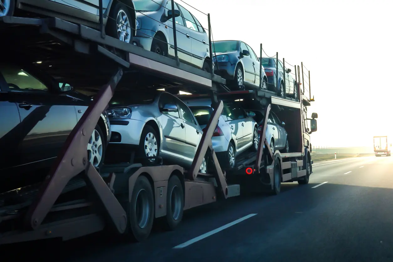 New Project (15) A truck carrying multiple new cars on a highway.