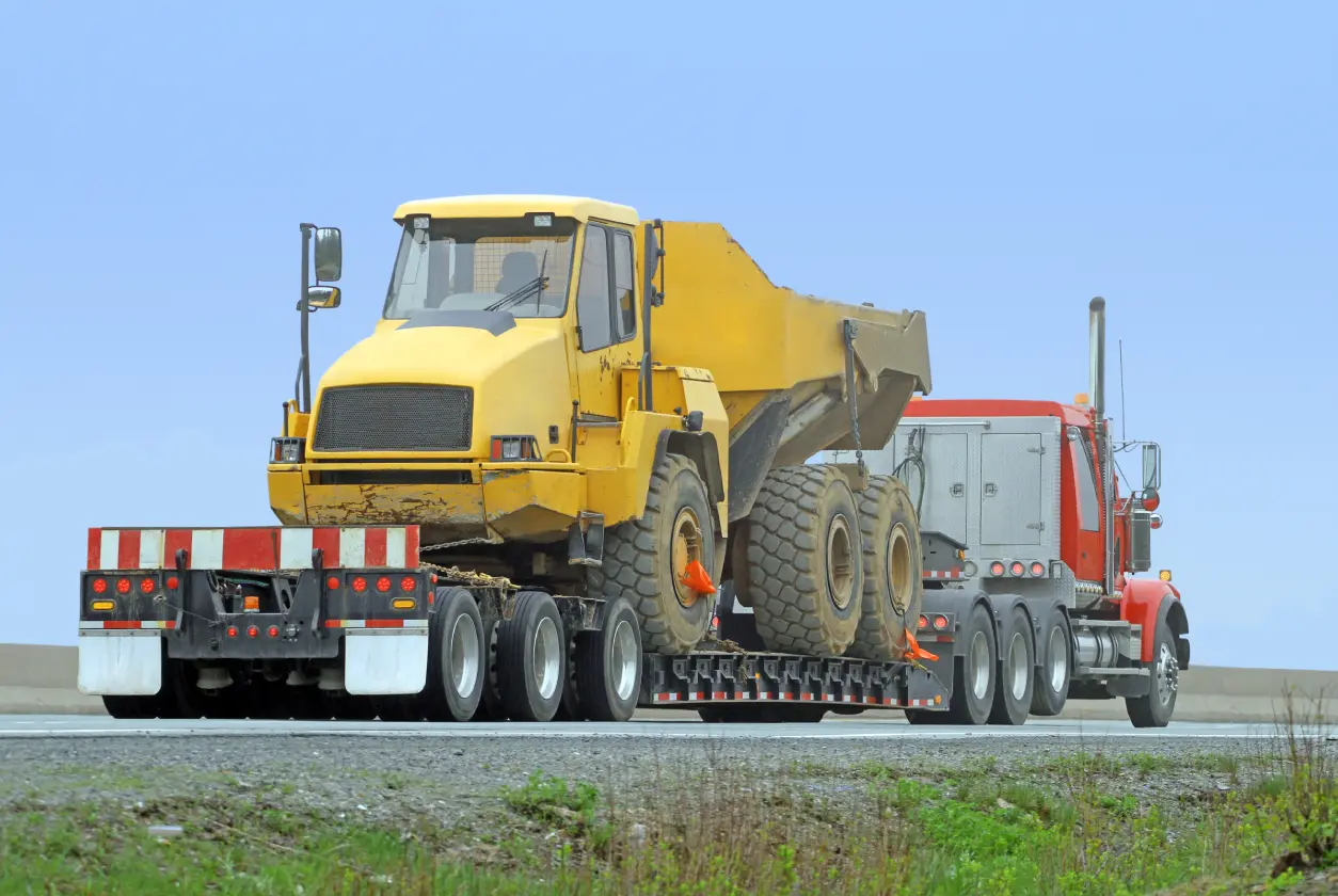 New Project (4) Red truck transporting large yellow construction vehicle.