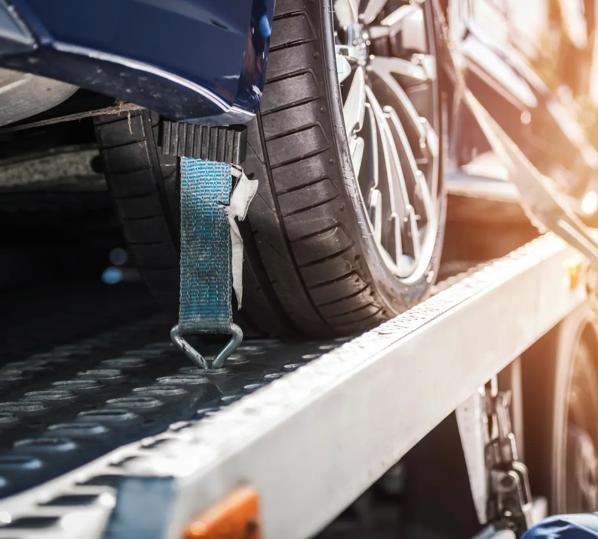 Close-up of a car tire on a ramp secured with a strap.