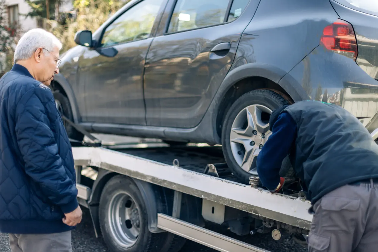 New Project(5) A car being loaded onto a tow truck by two workers.