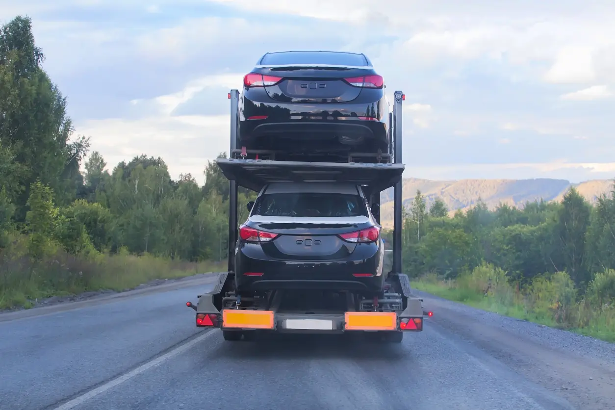 New Project(6) Car transporter carrying two vehicles on road.